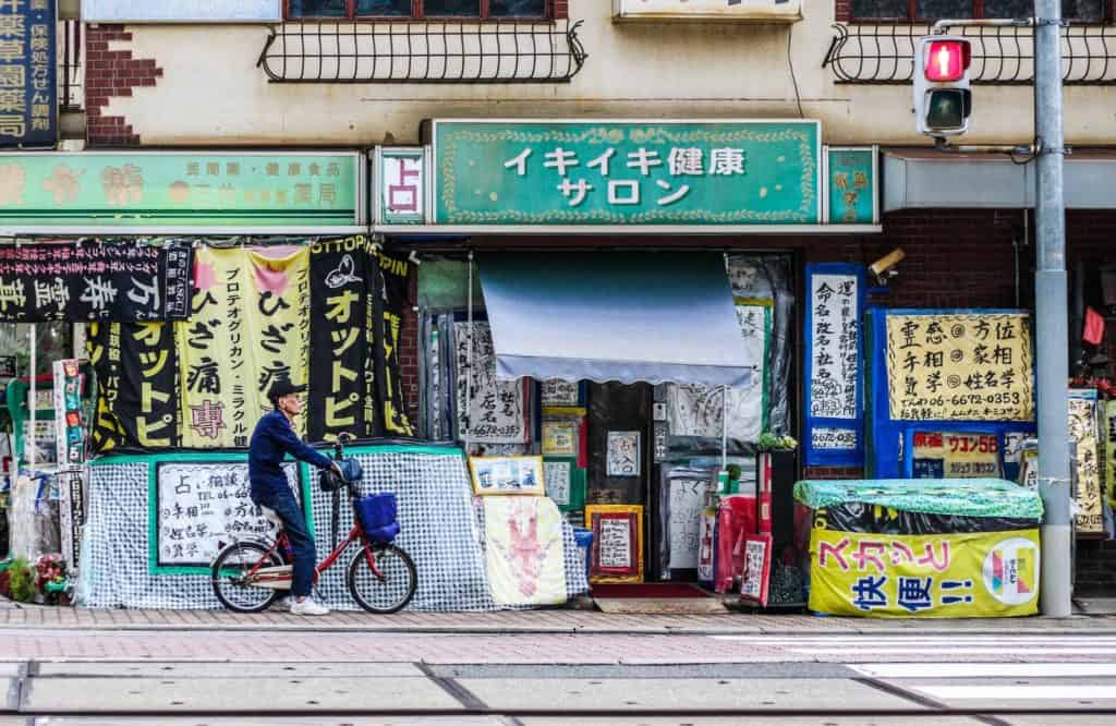 1-day osaka itinerary - an old man on his bicycle waiting in front of an old shop in Osaka