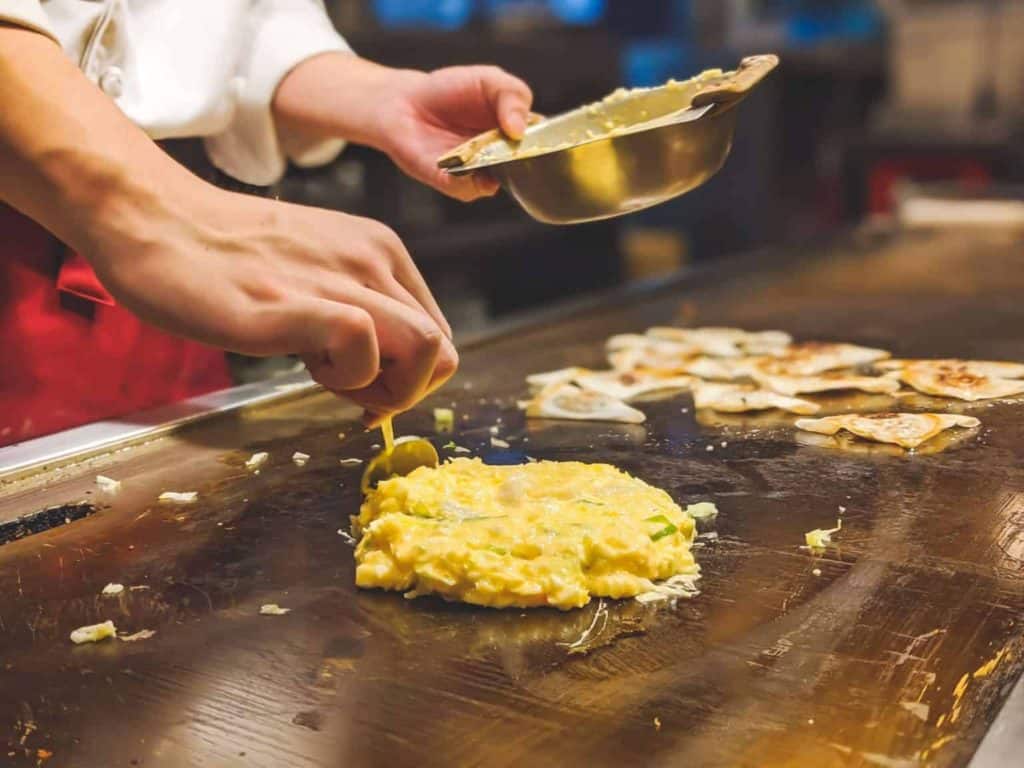 osaka 1 day itinerary - a chef is grilling the okonomiyaki batter on the hot plate