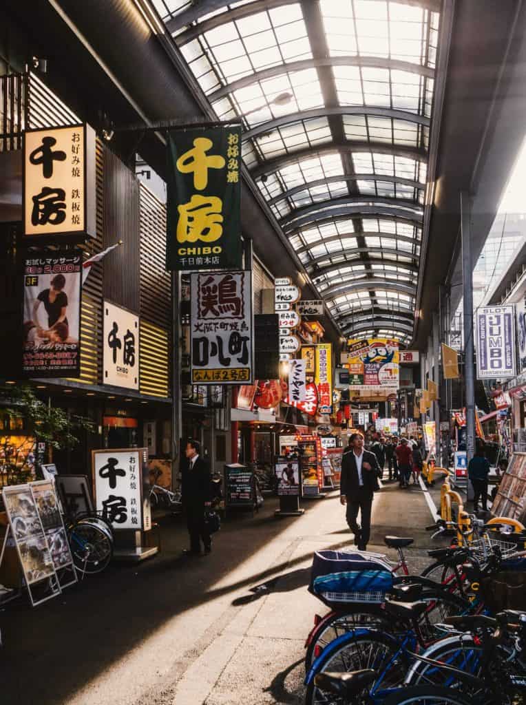 osaka itinerary 1 day - a guy walking down a covered market in Osaka