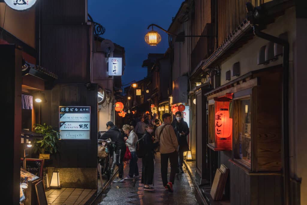 night time in kyoto - visitors walking down Pontocho Alley with red lanterns lining the street