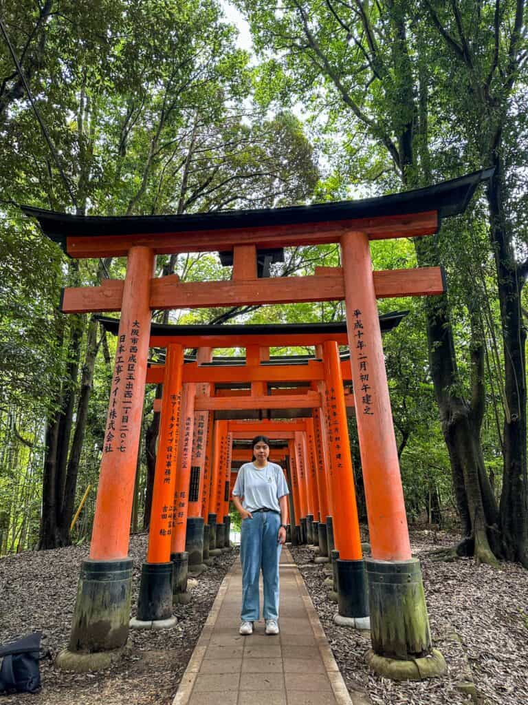photography spots in kyoto - Me taking photo with the famous torii gates in Fushimi Inari Shrine after the hike