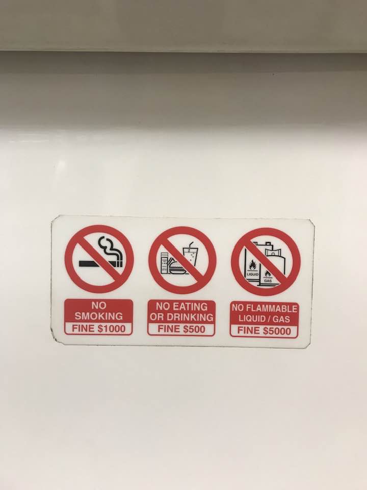 singapore etiquette for tourists - the no smoking, eating and flammable items signs on Singapore MRT