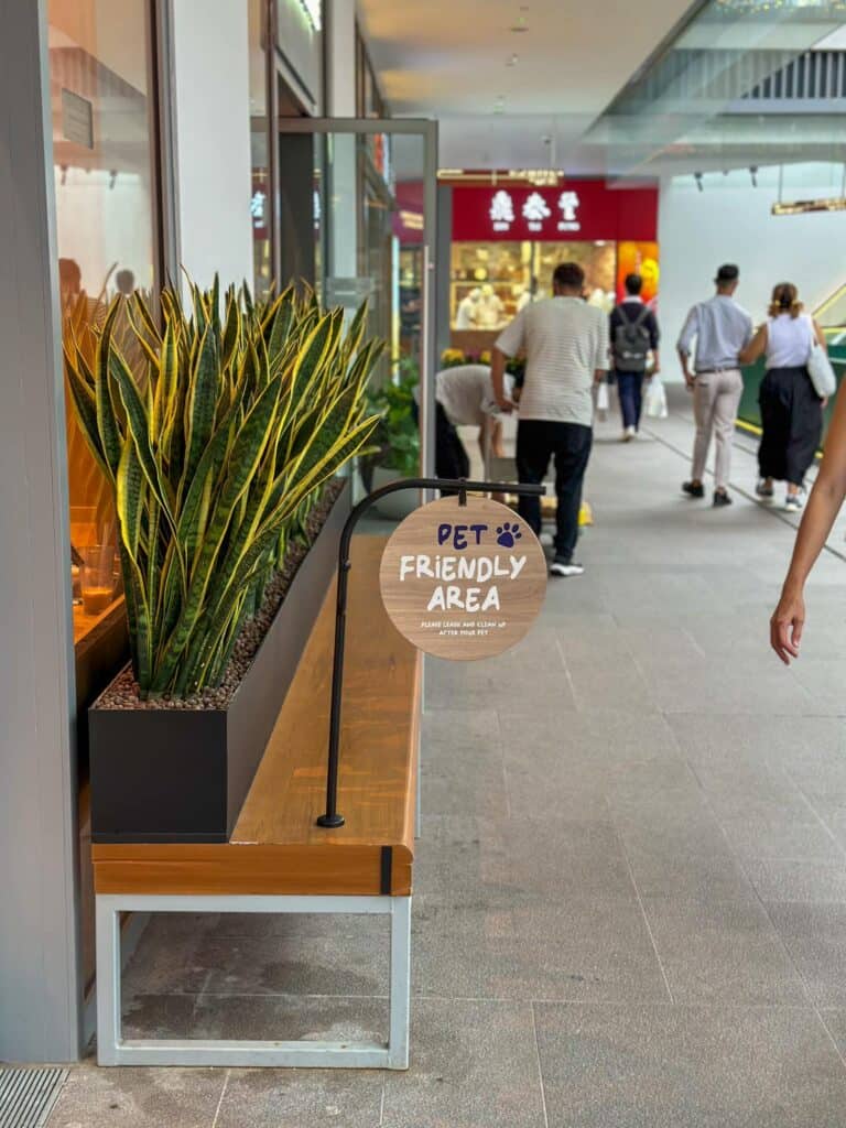 sg dog cafe - a pet-friendly area sign with a bench is found at One Holland Village, a pet-friendly mall in Singapore.