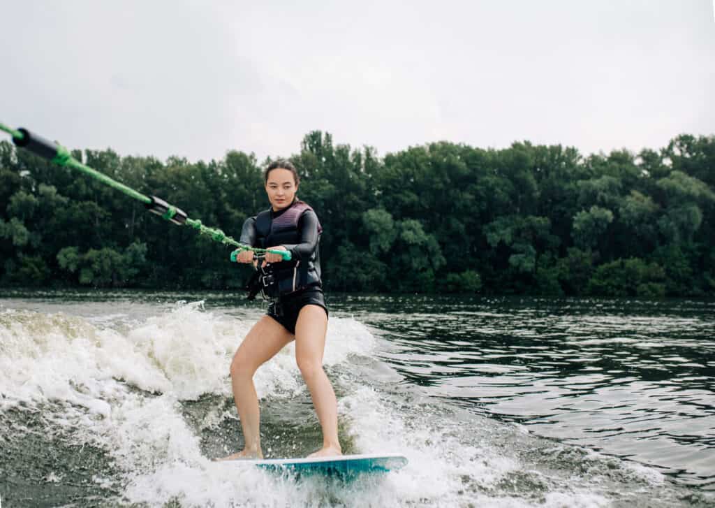 singapore wakesurfing - a girl is standing on a boat while holding onto the boat rope during wakesurfing