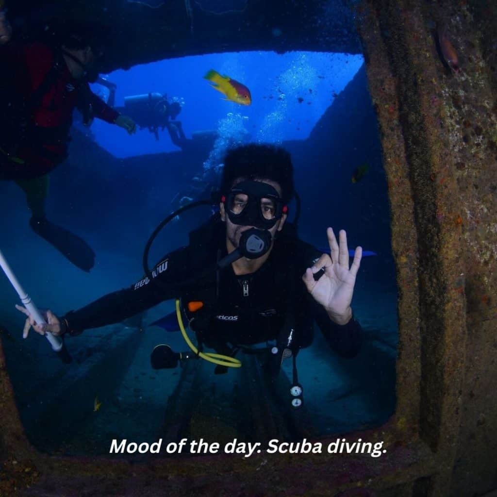 short scuba diving quotes - a scuba diver holding a camera signalling "OK" underwater