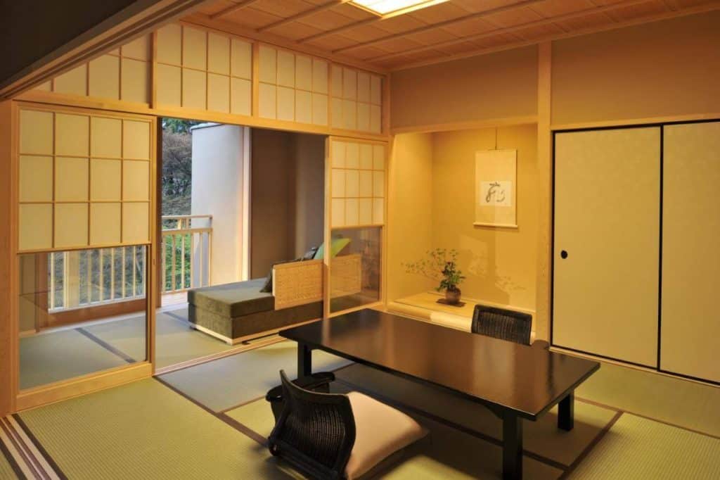 hakone hotel with private onsen - a traditional ryokan room with tatami flooring opens up to the beautiful view of the lush greenery at Gora Kadan