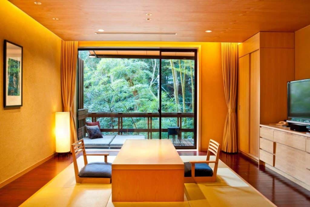 ryokan in hakone with private onsen - an indoor and outdoor seating area surrounded by lush greenery in one of the luxurious rooms at Hakone Suishoen