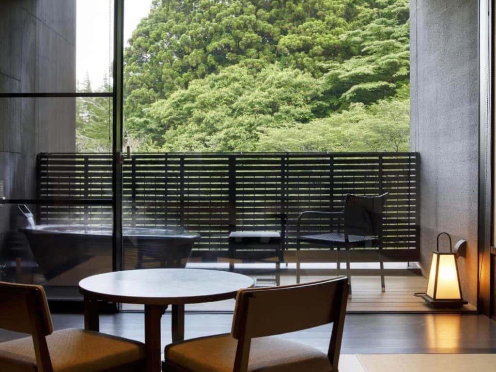 ryokan with private onsen hakone - two chairs and a table in the room overlooking the lush greenery at Hakone Kowakien Tenyu