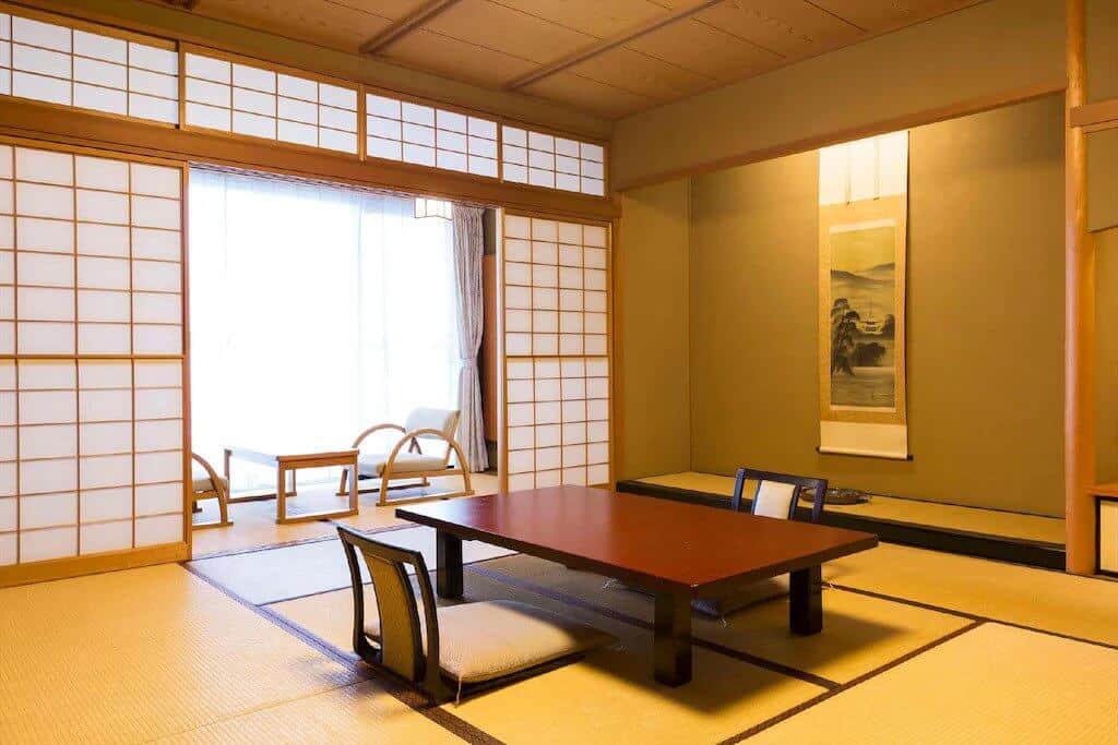kanazawa ryokan with private onsen - the low seating area of a Japanese-style room 
 with tatami flooring at Kuriya Yasohachi