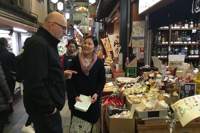 food tours kyoto - a guide explaining the food in Nishiki Market to a participant