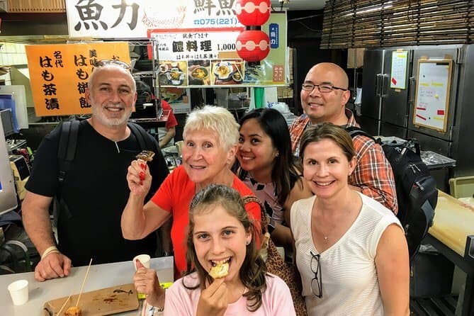 food tours kyoto - a group of participants taking picture together in front of a food stall in Kyoto