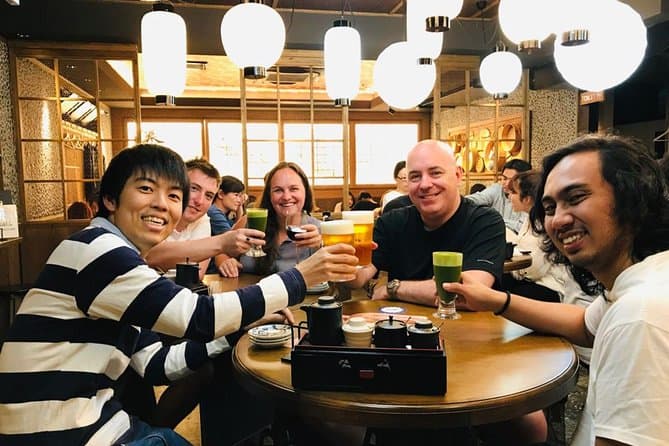kyoto food tours - a group of participants posing with a cup of alcoholic drinks in one of the Kyoto bars