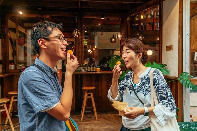 kyoto food tours - two people putting Kyoto snacks into their mouths