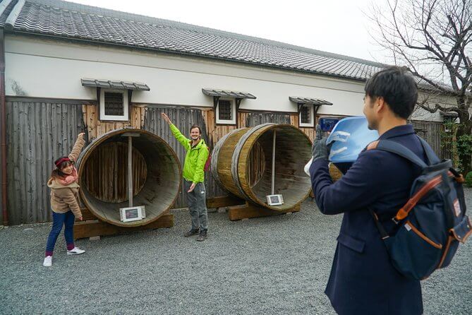 GEKKEIKAN OKURA SAKE MUSEUM - the guide is helping the participants taking photo with the sake barrel that used to brew sake