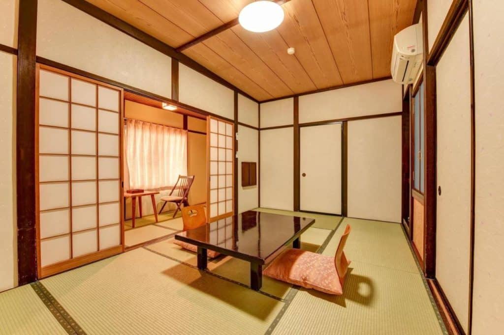 ryokan onsen takayama - the seating area with a table and 2 seats in a tatami-floored room at Hidatakayama Futarishizuka Hakuun