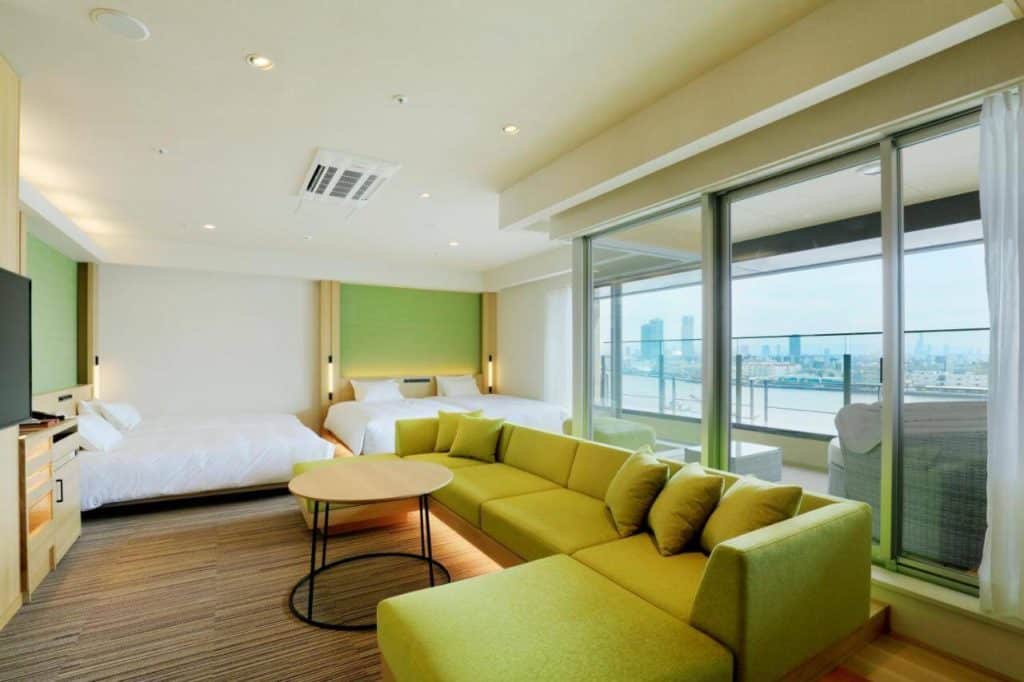 hotels in osaka with private onsen - a room with a big sofa bed and windows overlooking the bay at THE SINGULARI HOTEL & SKYSPA