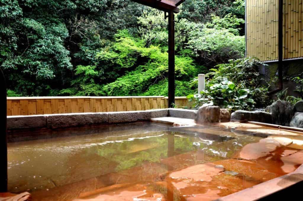 osaka ryokan private onsen - the open-air onsen bath surrounded with lush greenery at Okumizuma Onsen