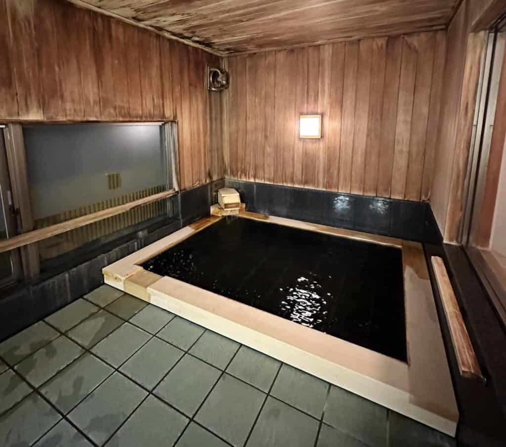 ryokan onsen osaka - a private onsen bath in the ryokan at night