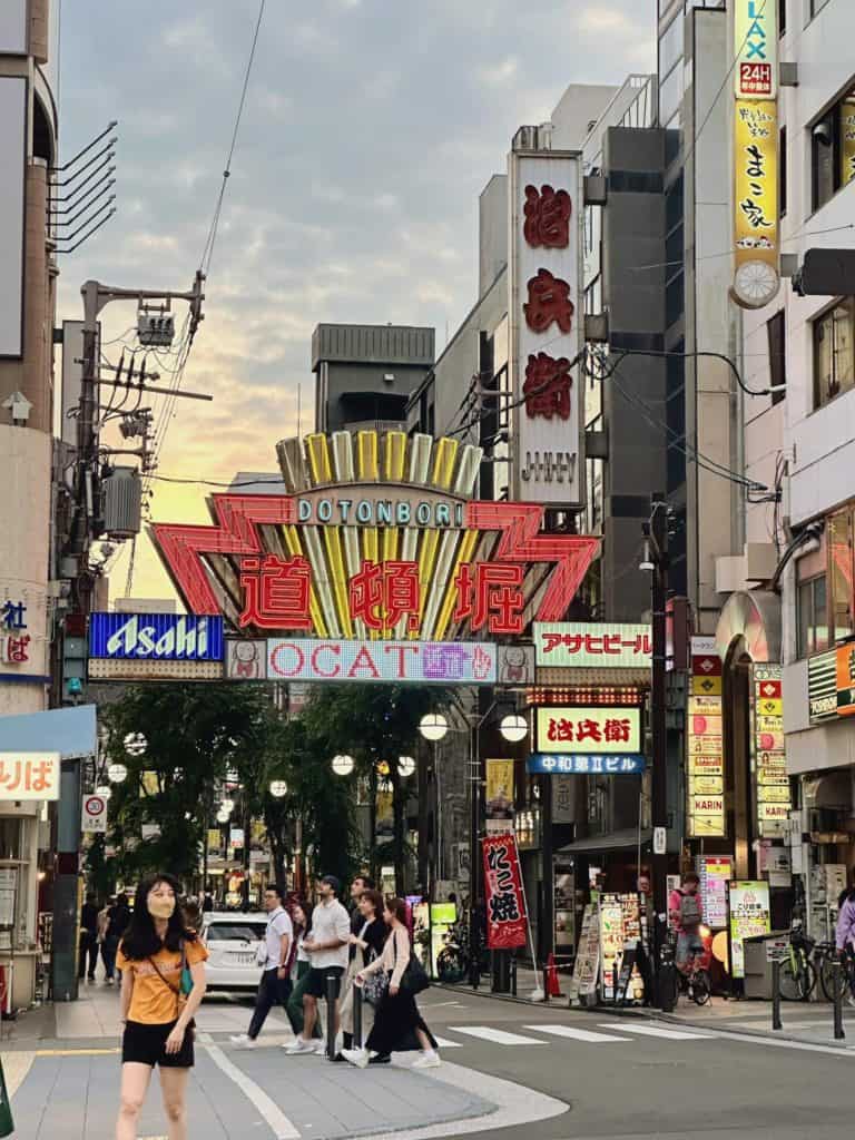 is osaka safe - people walking in front of the colourful Dotonbori sign in Osaka during sunset