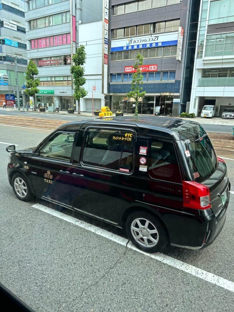 is osaka safe at night - a local black-coloured taxi cruising the road in Osaka