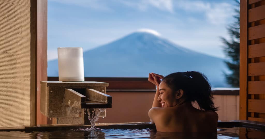 best mt fuji ryokan with private onsen - a lady is soaking in a private onsen bath in a ryokan overlooking the Mount Fuji
