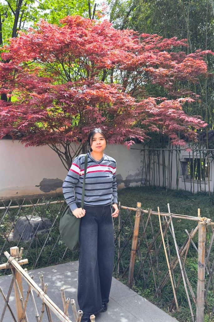 Japan Fall Autumn Packing List - me standing in front of an orangy red tree donning knit sweater and black jeans