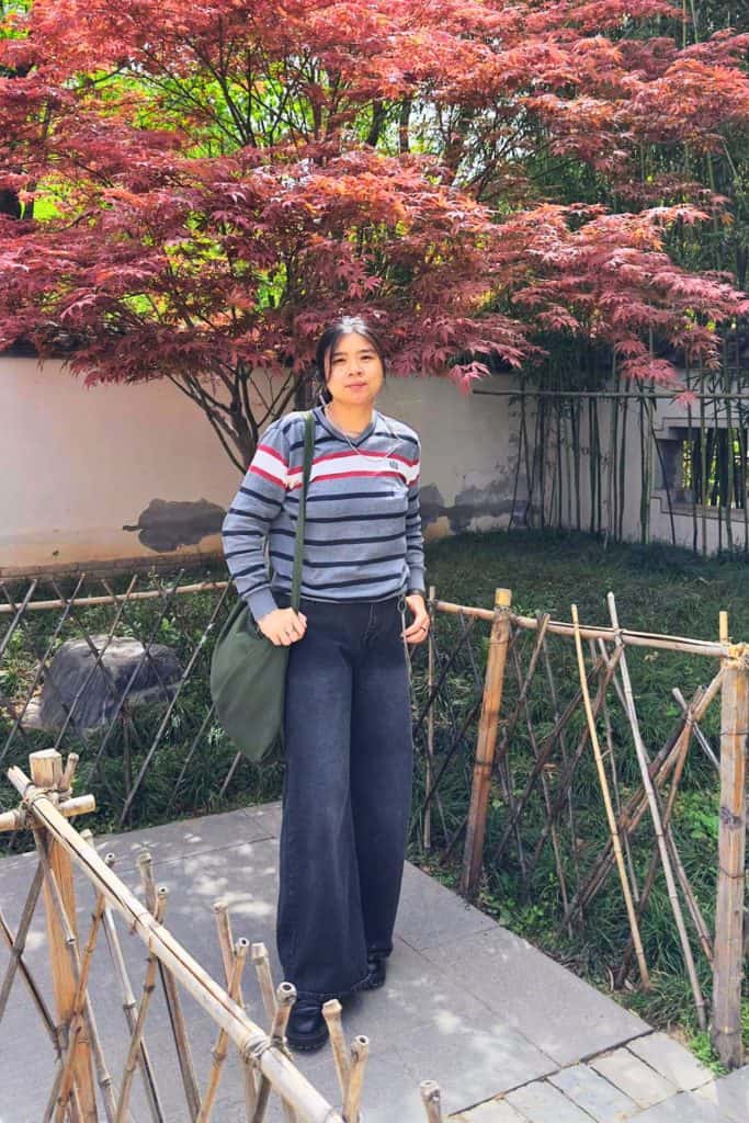 osaka fall outfit ideas - me wearing a knitted sweater and long black jeans with a reddish brown tree as the backdrop