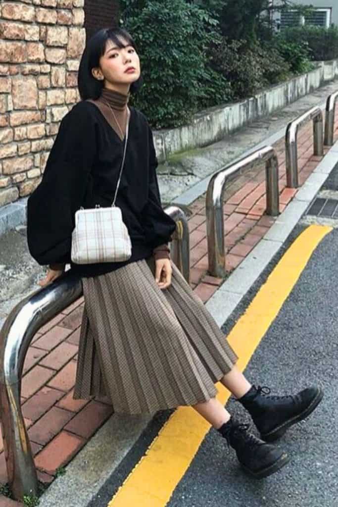 japan fall travel outifts ideas -  a lady dressed in brown turtleneck sweater and black outer with pleated maxi skirt and black boots with white crossbody bag