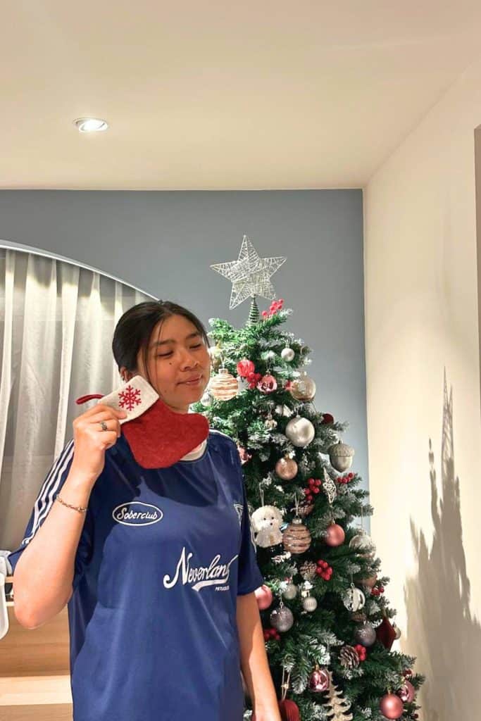 Festive woman in sports jersey with Christmas tree and holiday decorations in background. (best Christmas gift ideas for Japan lovers)