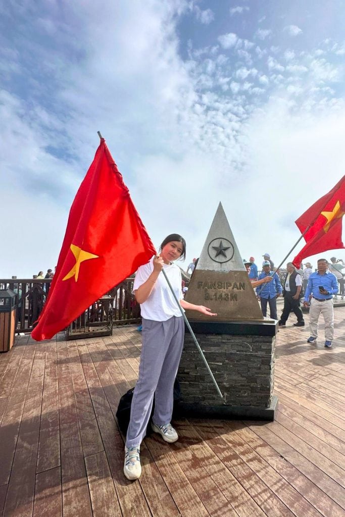 Sam Lee Travel - we holding a Vietnam flag at the summit of Fansipan near Sapa, Vietnam
