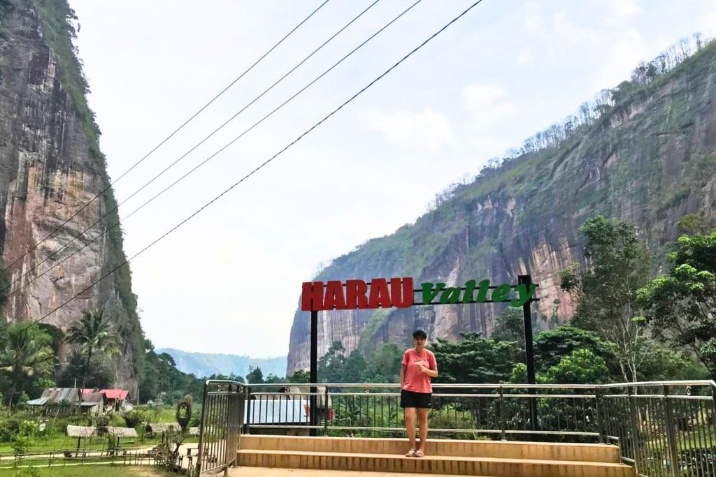 Sam Lee Travel - me standing in front of the Harau Valley sign with mountains as backdrop